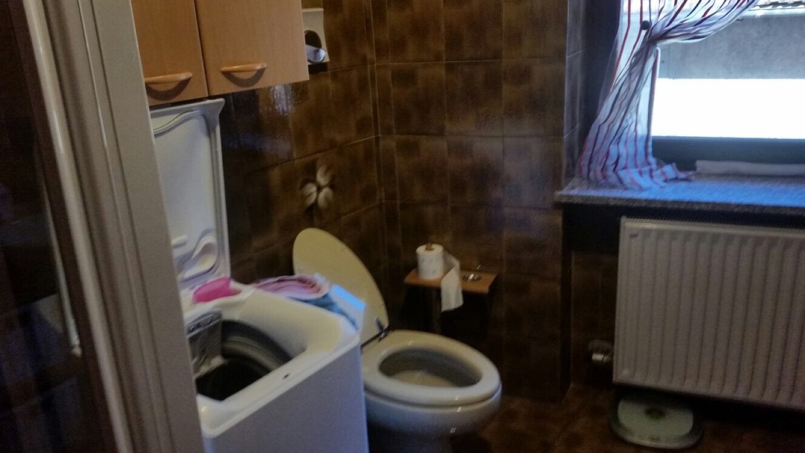 Bagno a Roncone prima dell'intervento con finiture scure e lavanderia a vista