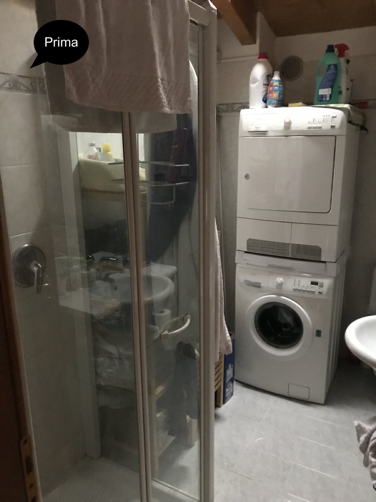 Bagno mansardato prima dell'intervento con doccia datata e lavanderia a vista