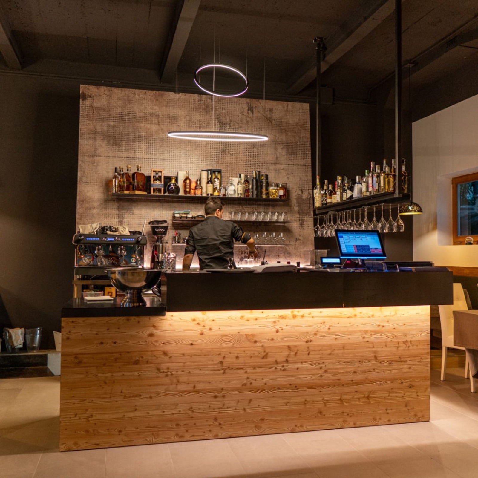 Bancone del ristorante Emozioni a Riva del Garda dopo l'intervento con legno, luce scenografica e attrezzatura integrata