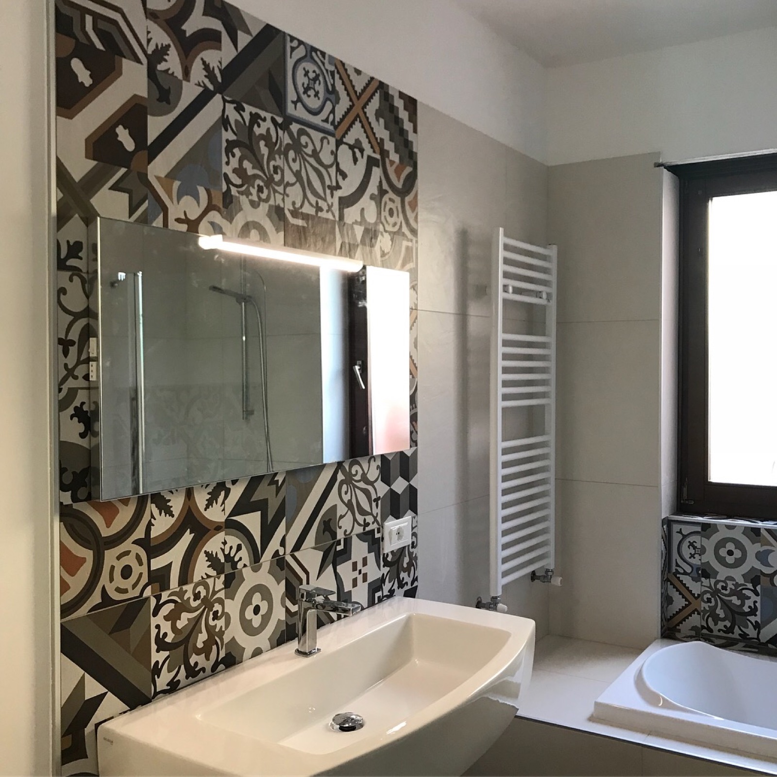 Bagno Farina a Riva del Garda dopo l'intervento con rivestimento decorativo, arredo sospeso e nuova illuminazione